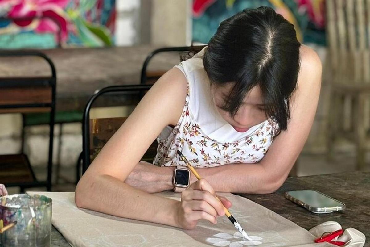 a woman sitting at a table writing with a pencil