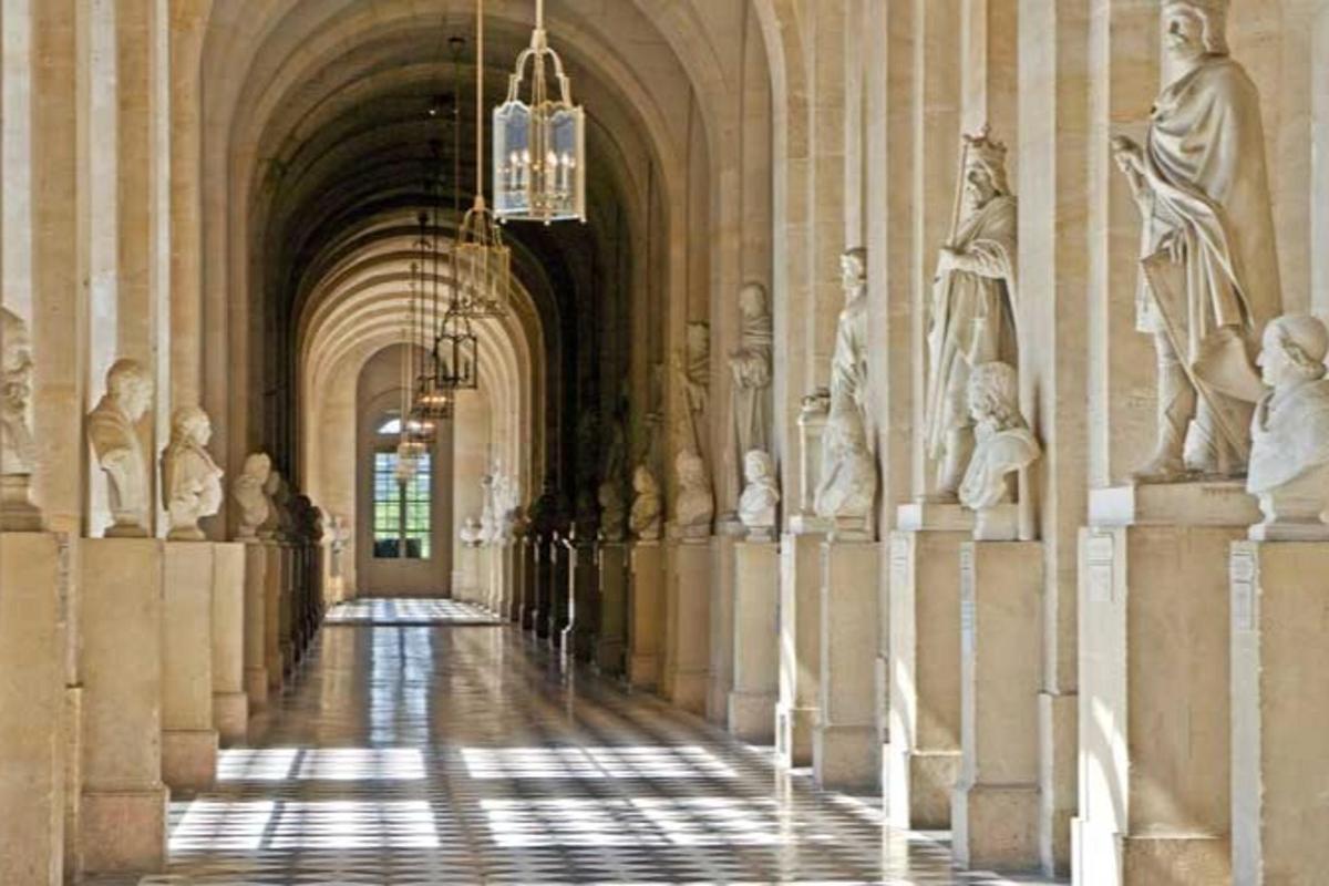 a hallway in a building with statues and a chandelier