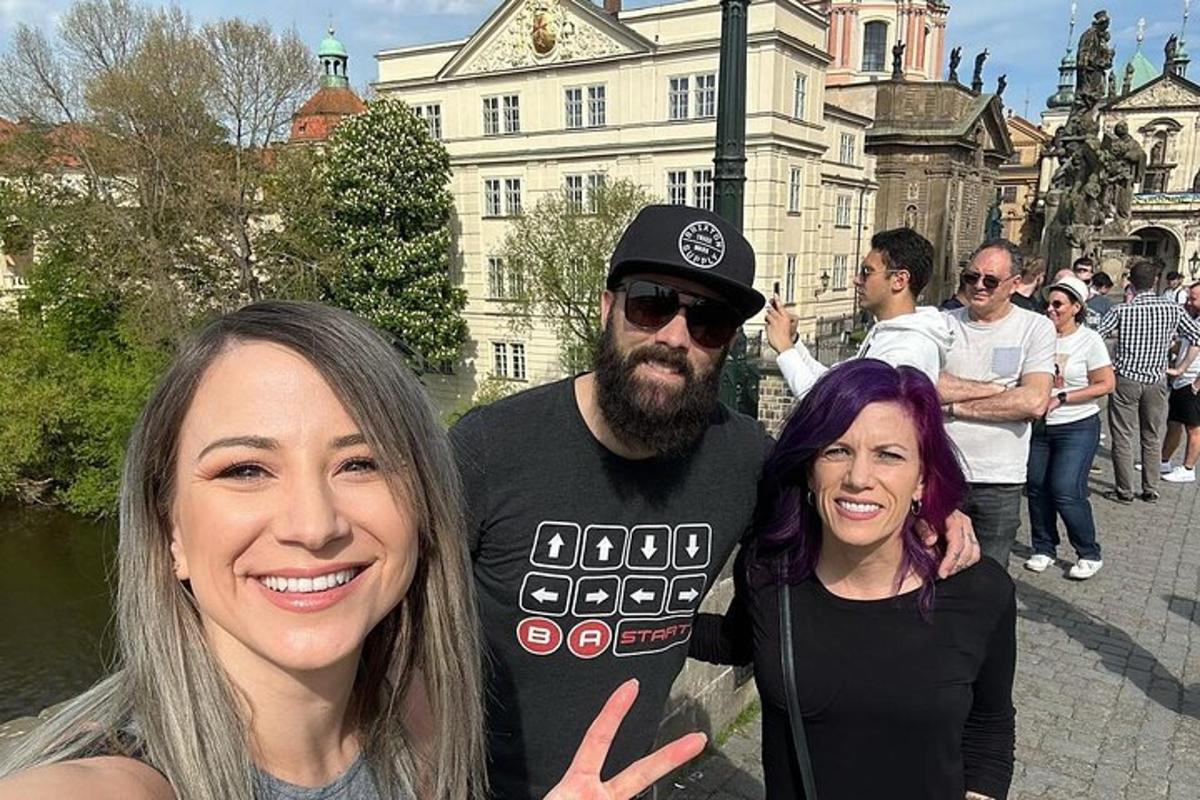um homem e duas mulheres em pé em frente a um prédio