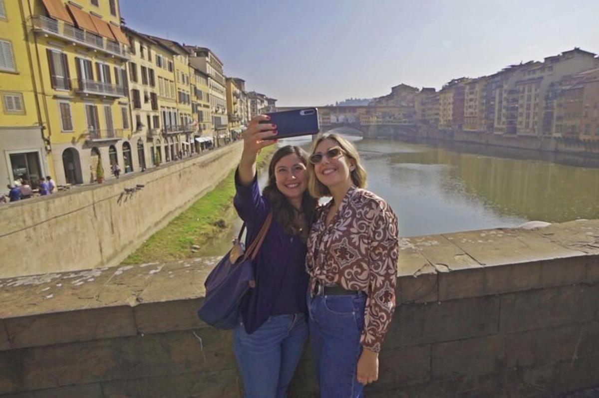 due donne in piedi accanto a un fiume che scattano una foto