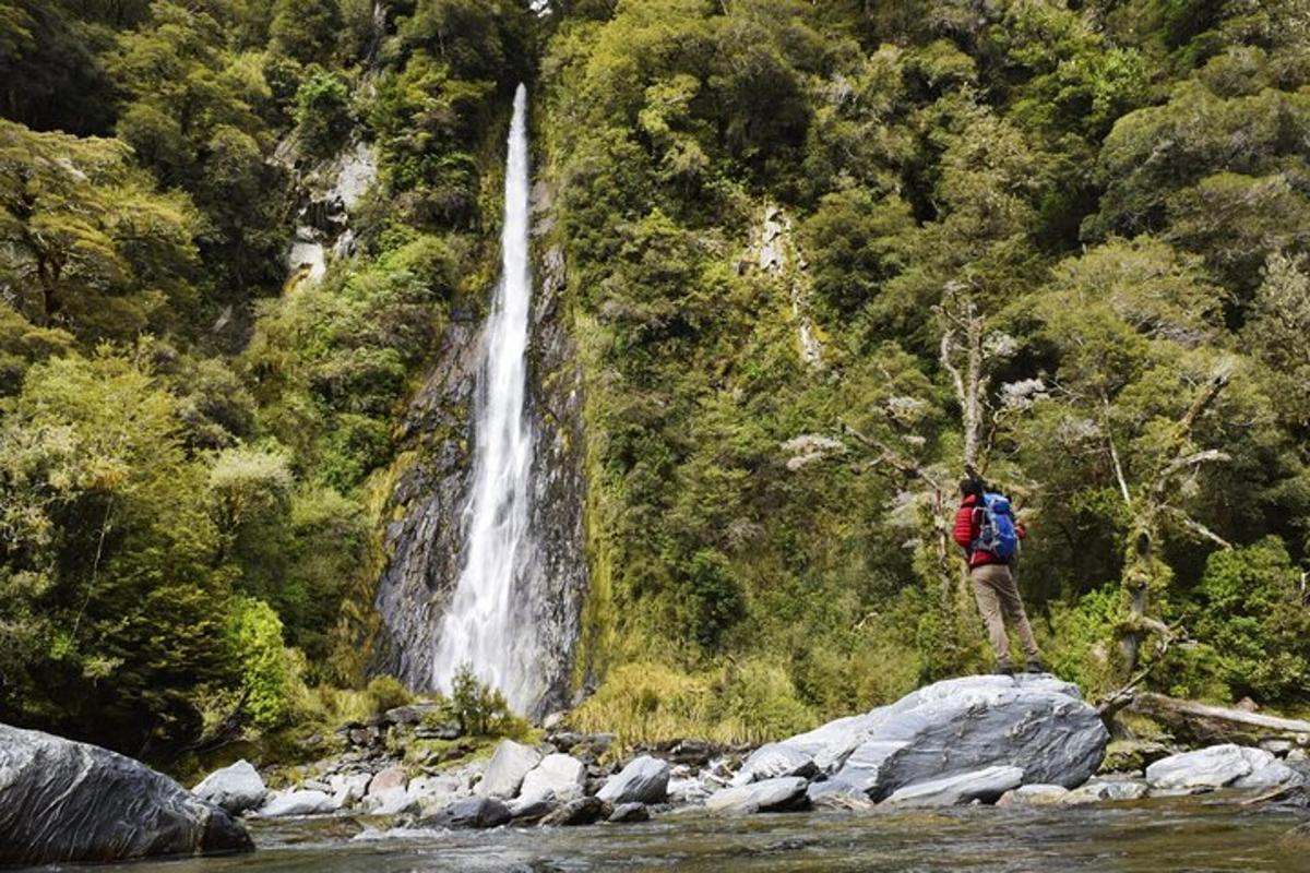 a man standing on rocks in front of a waterfall