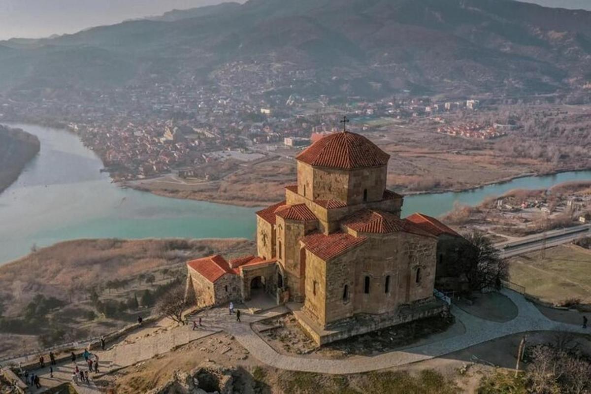 Un edificio antiguo en la cima de una colina junto a un río.
