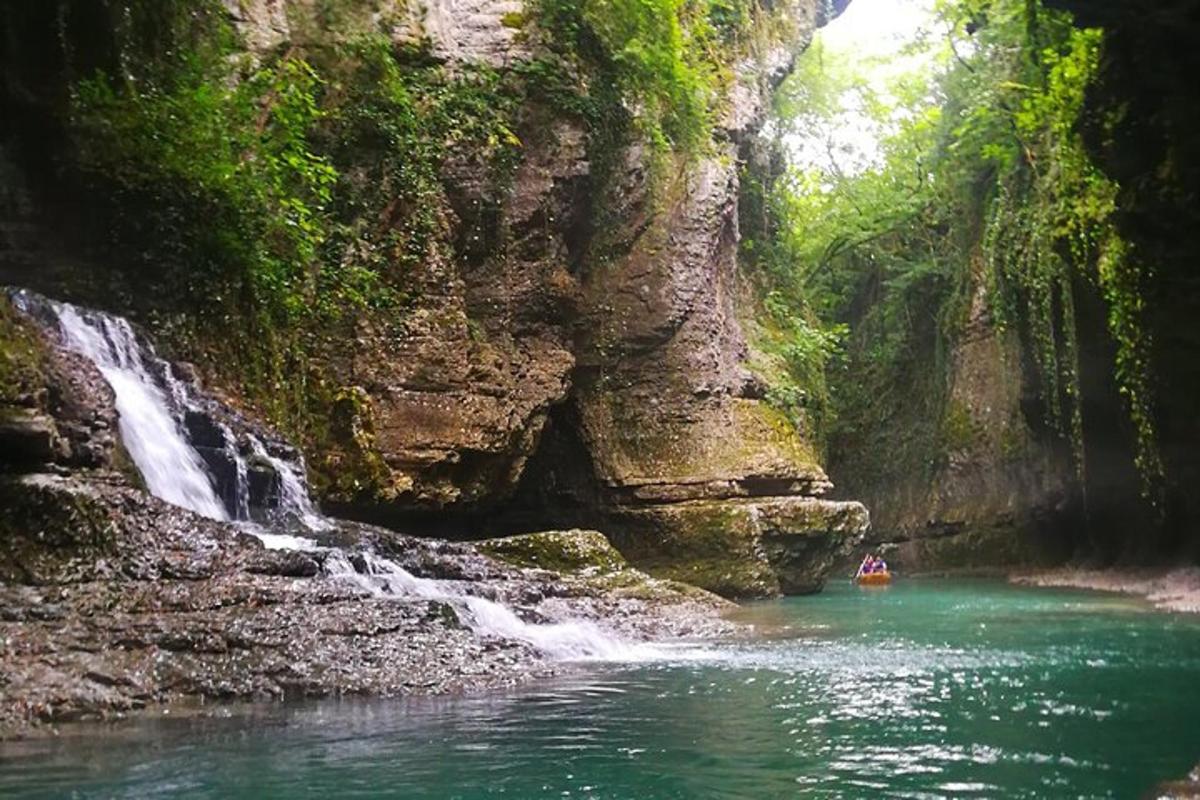 una persona su una barca in un fiume accanto a una cascata