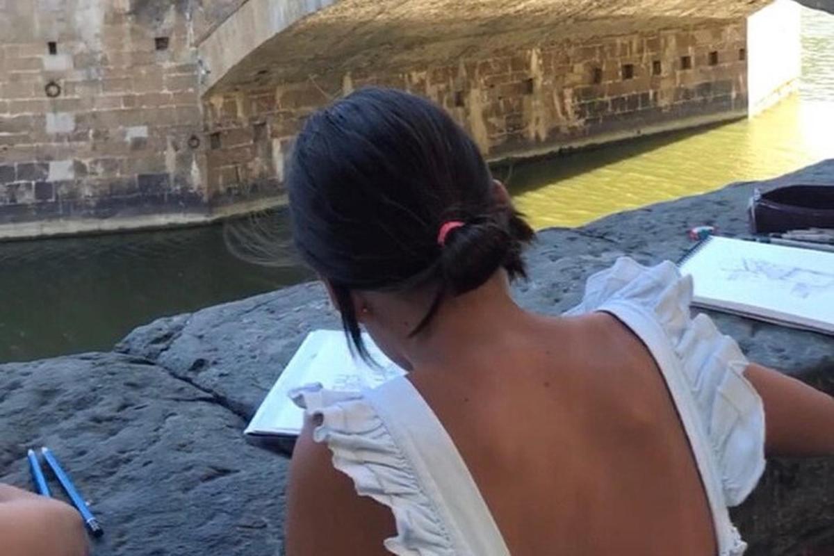 uma mulher sentada em uma rocha olhando para a água