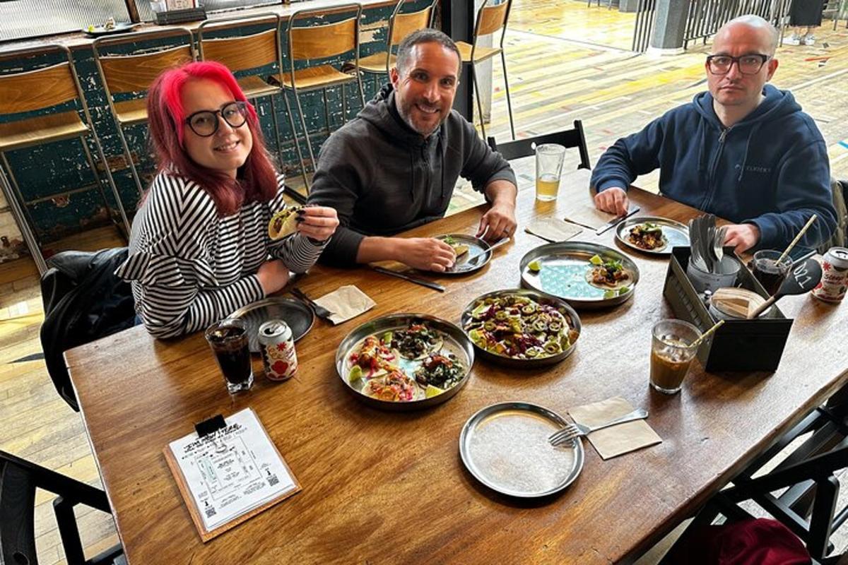 Tres personas sentadas en una mesa con platos de comida.