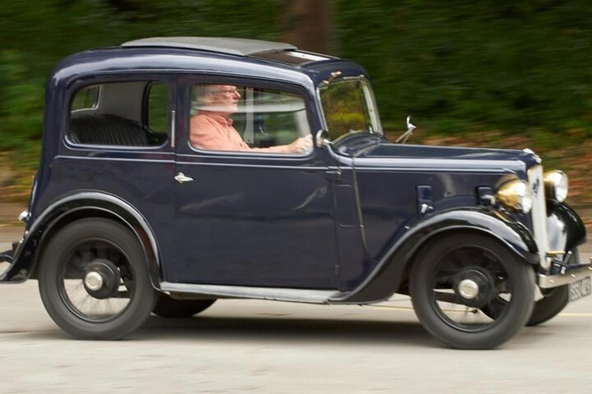 a man driving a blue car on a road