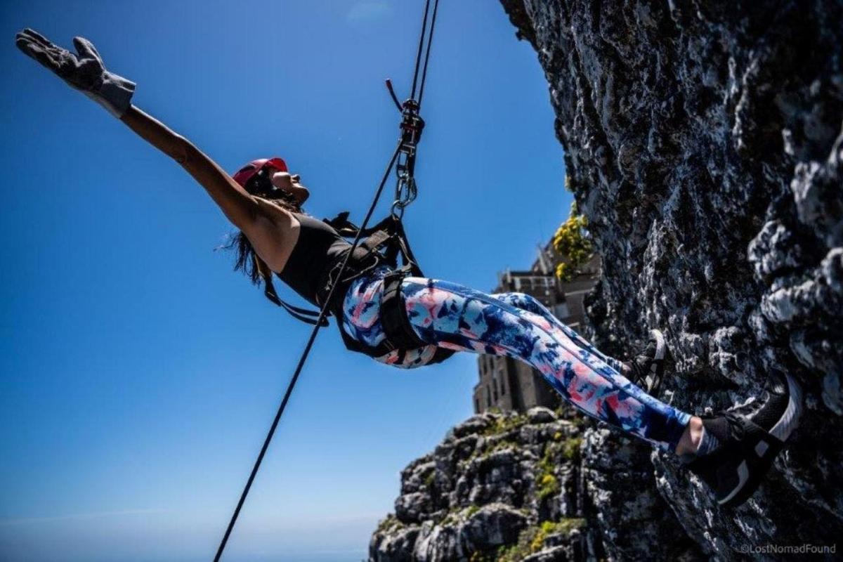 seorang wanita berada di garisan rappelling di atas tebing