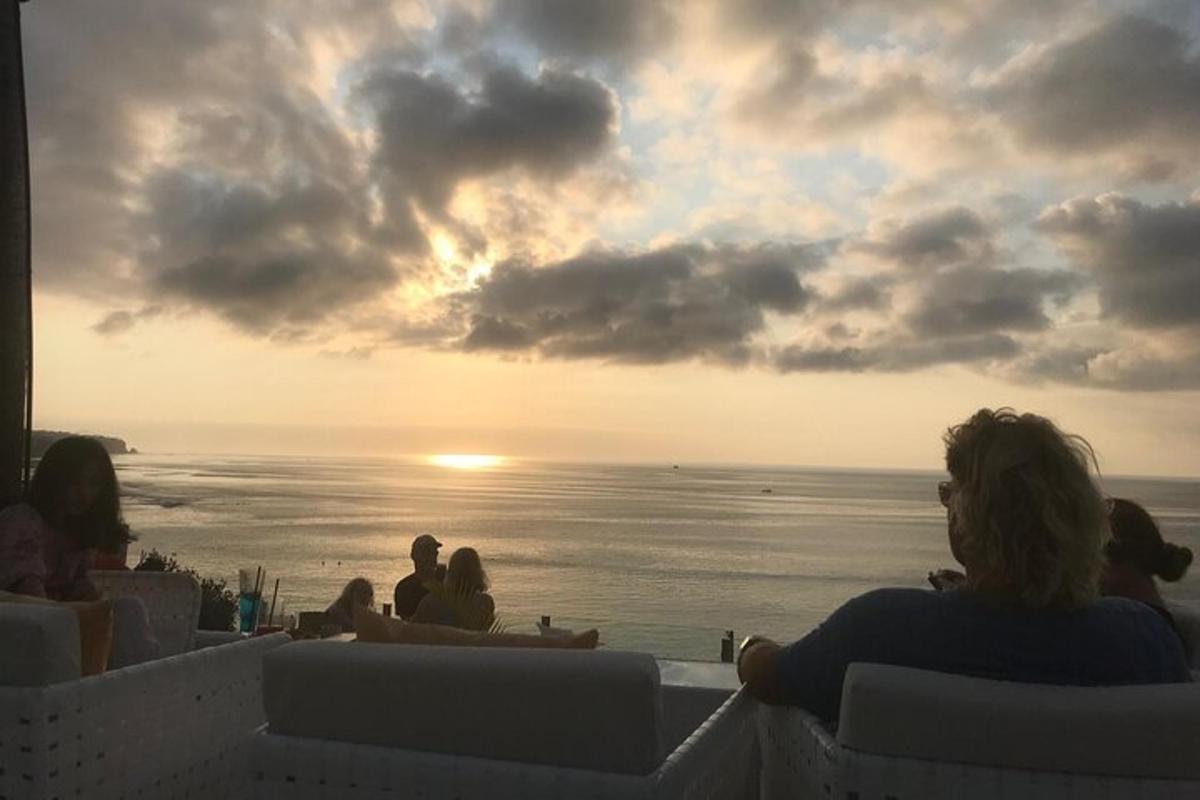 Un grupo de personas sentadas en la playa viendo la puesta de sol