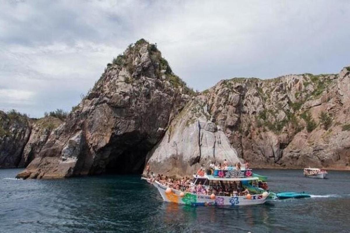 Un grupo de personas en un barco frente a una formación rocosa.