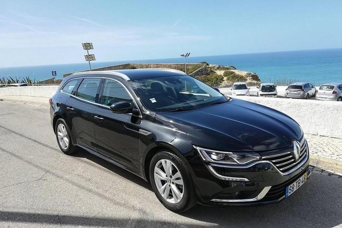 en svart bil parkert på en vei nær stranden