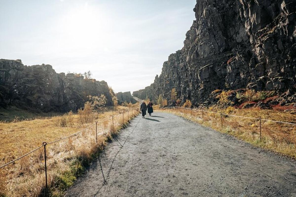 to personer som går nedover en vei ved siden av et fjell