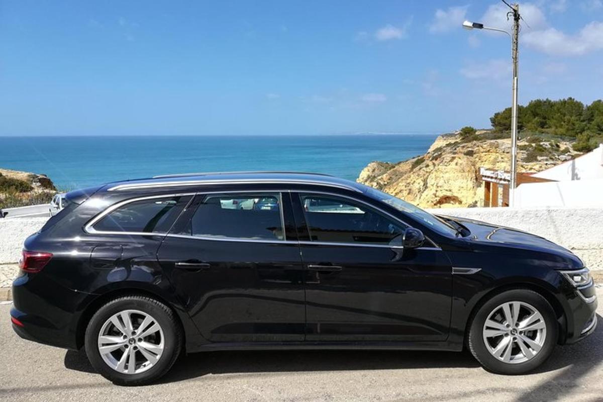 Un coche negro estacionado en una carretera cerca del océano.