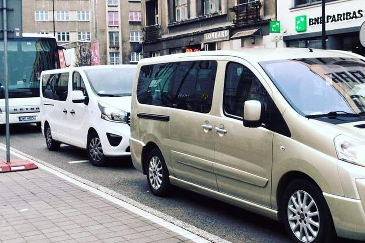 rad bielych dodávok zaparkovaných na mestskej ulici