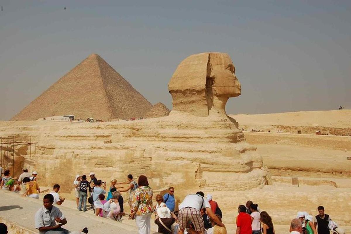 skupina lidí stojící kolem sochy před pyramidou