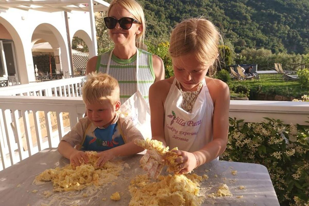 una donna e due bambini seduti a un tavolo che mangiano cibo