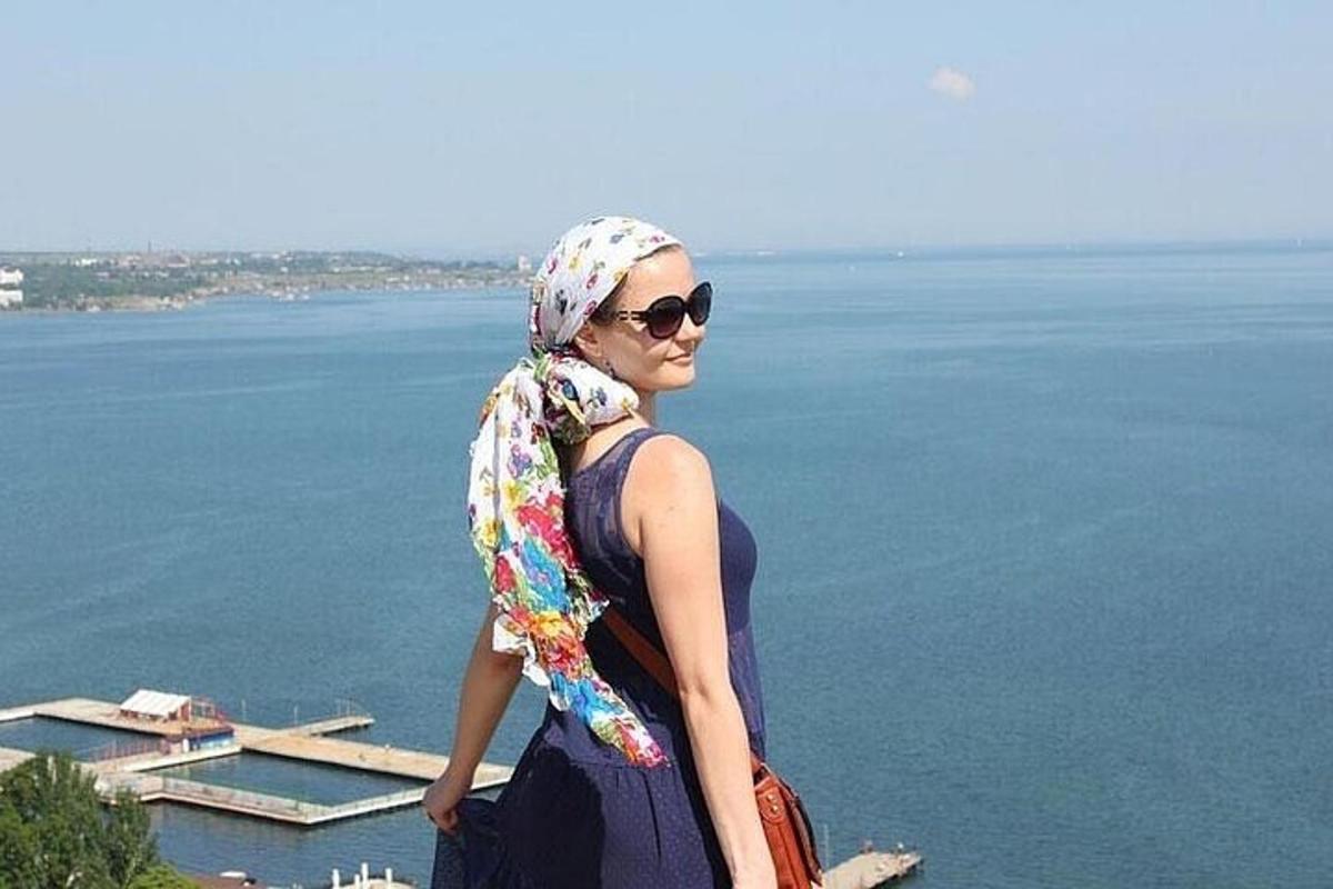μια γυναίκα που φοράει ένα μαντήλι και στέκεται δίπλα στο νερό