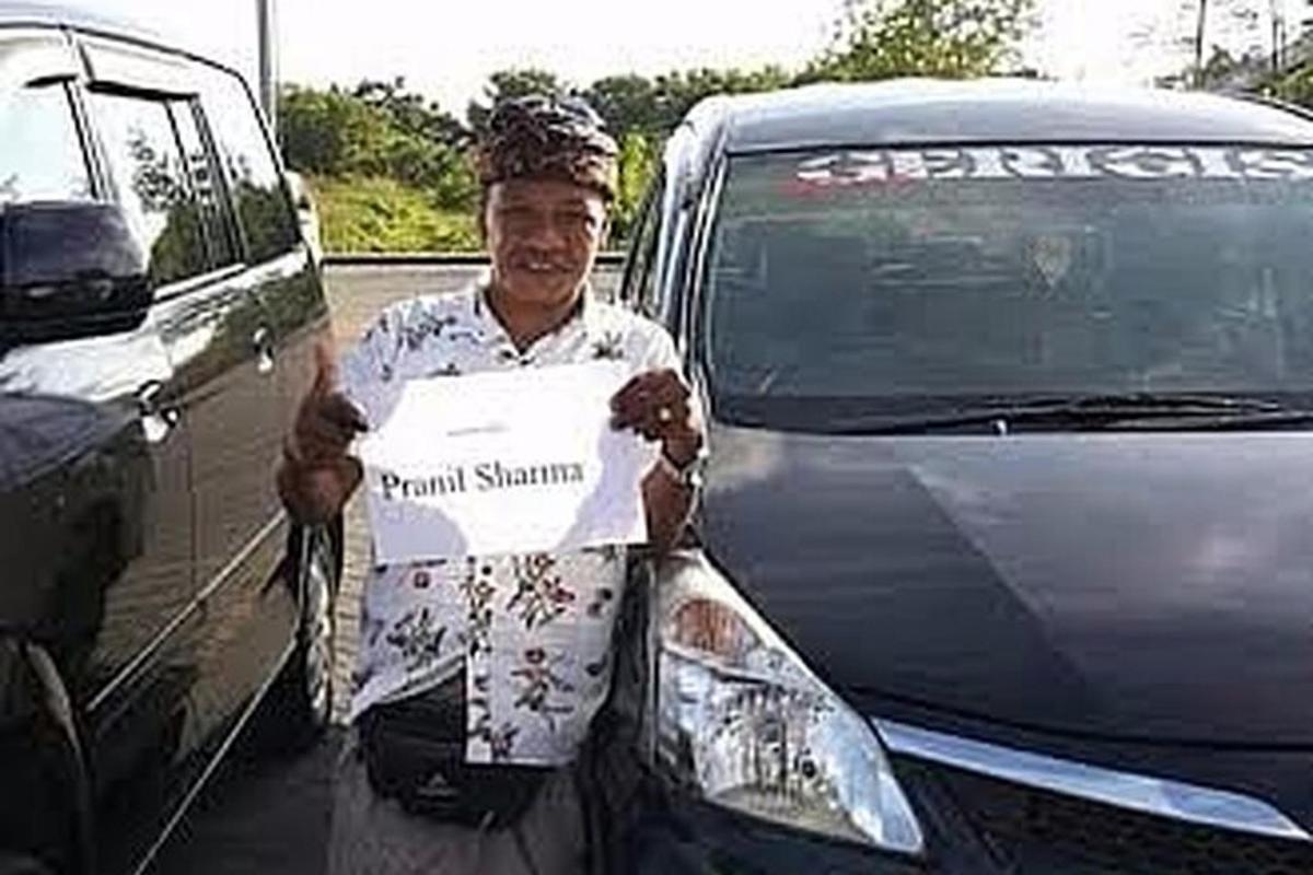 seorang lelaki memegang papan tanda di hadapan sebuah kereta