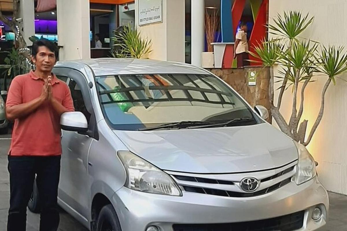 seorang lelaki berdiri di sebelah kereta perak