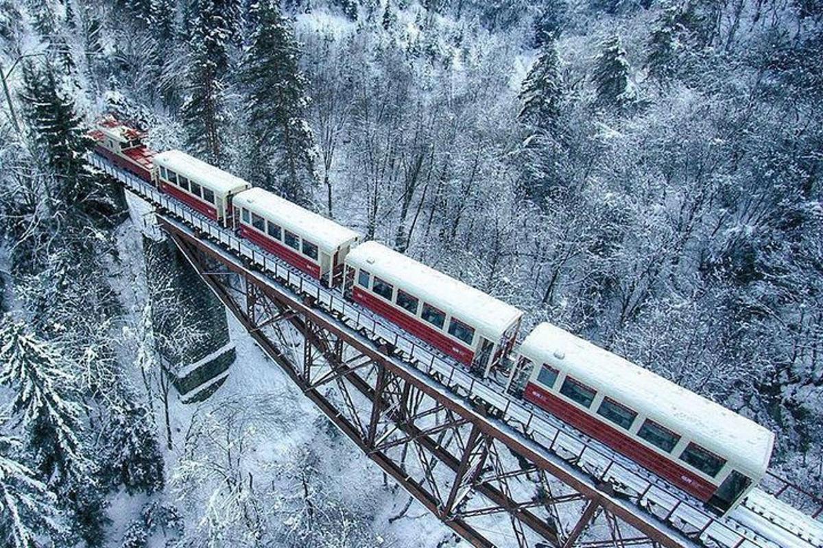 ein rot-weißer Zug auf einer Brücke im Schnee
