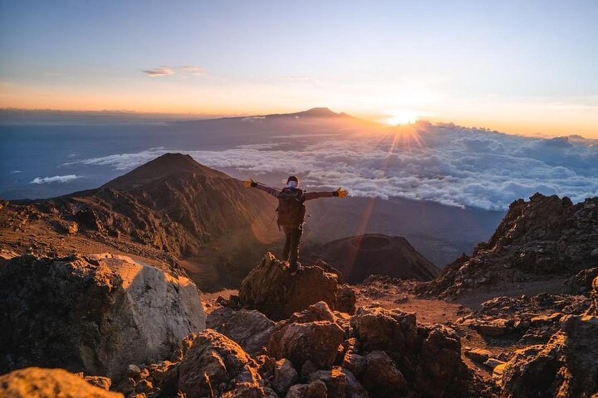 a man standing on top of a mountain with his arms out
