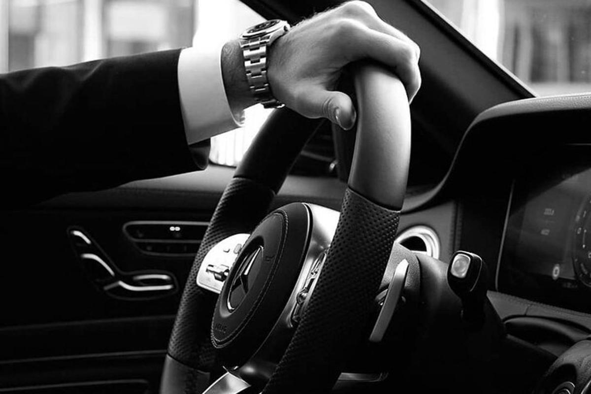 uma pessoa dirigindo um carro com a mão no volante