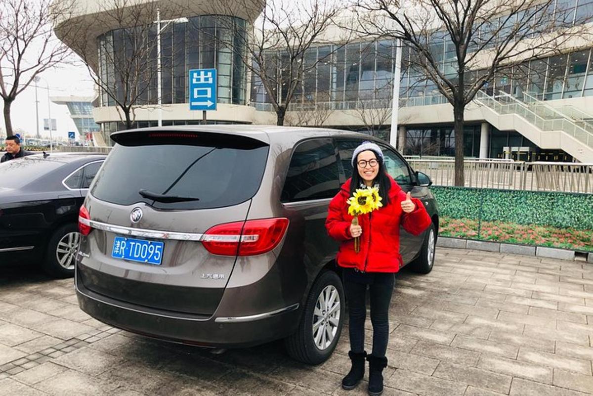 a woman holding a sunflower standing next to a car