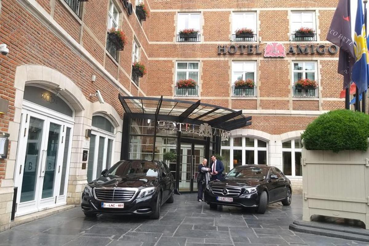 Dos personas paradas frente a un hotel con dos coches.