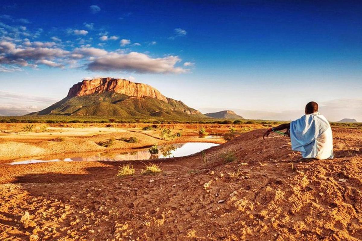 un homme assis sur une colline regardant une montagne