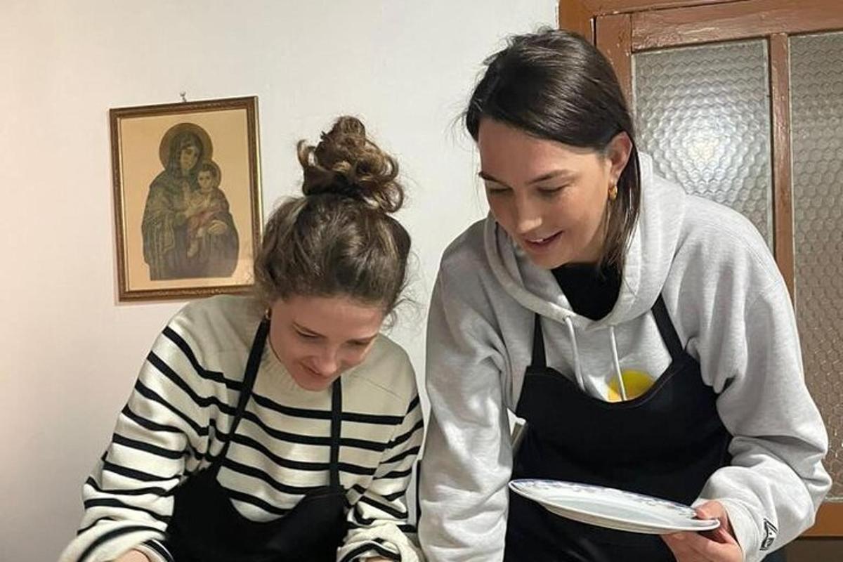 dvě ženy sedící vedle sebe a dívající se na talíř