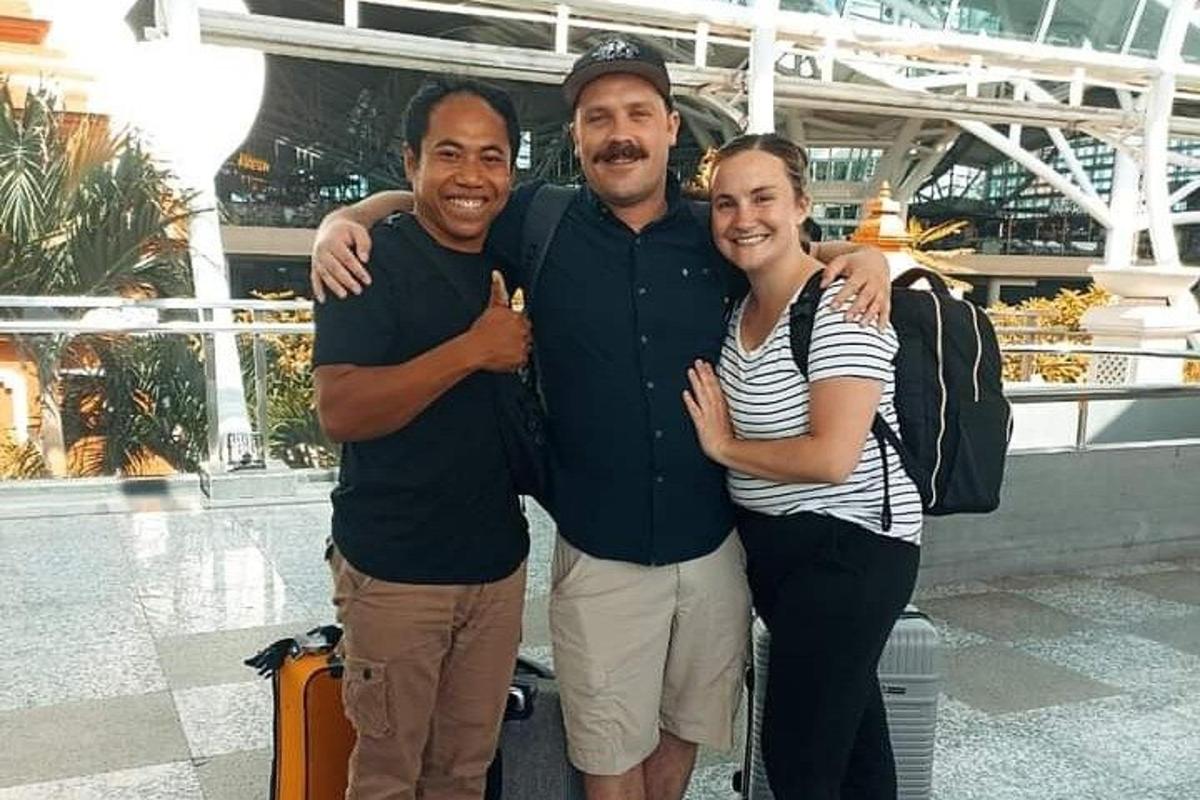 Két férfi és egy nő pózol egy képhez egy repülőtéren