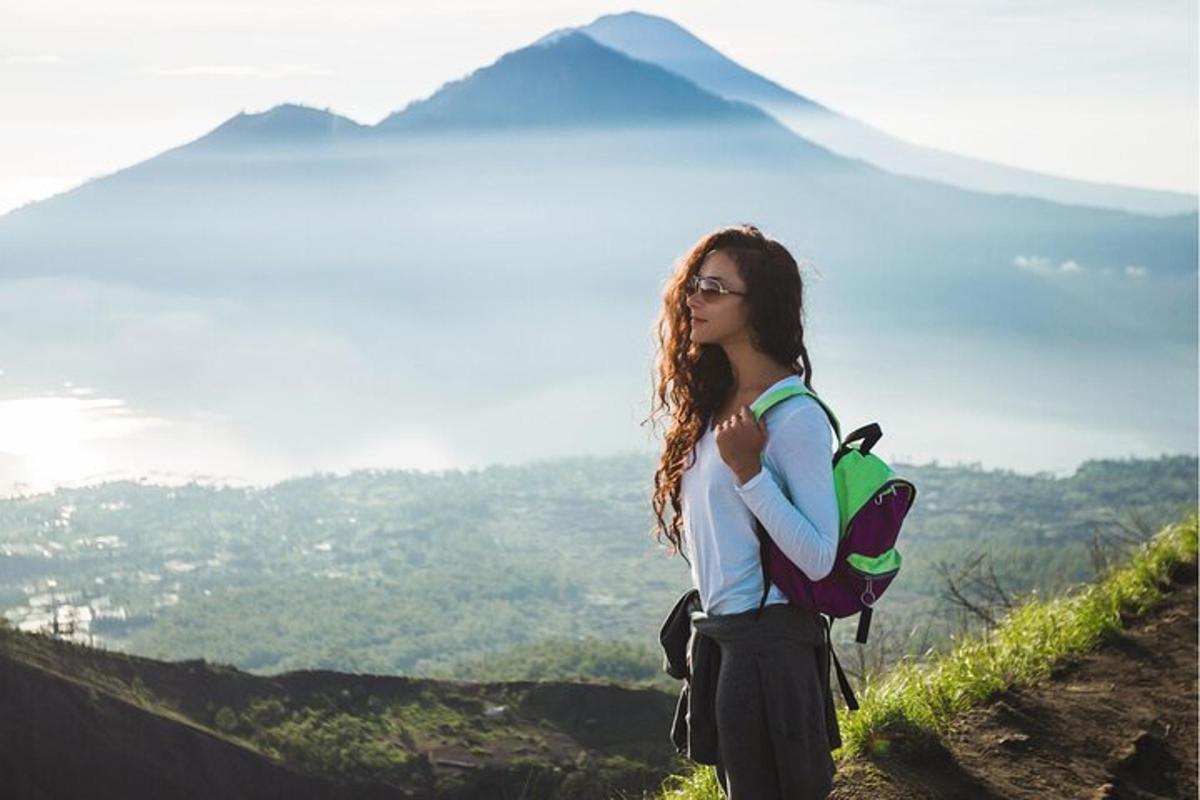 eine Frau mit einem Rucksack steht auf einem Berggipfel