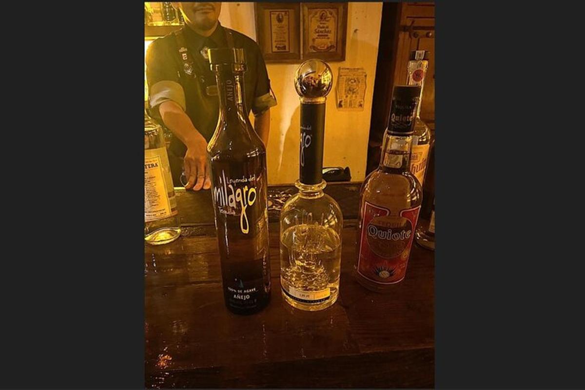 three bottles of alcohol on a counter with a man in the background