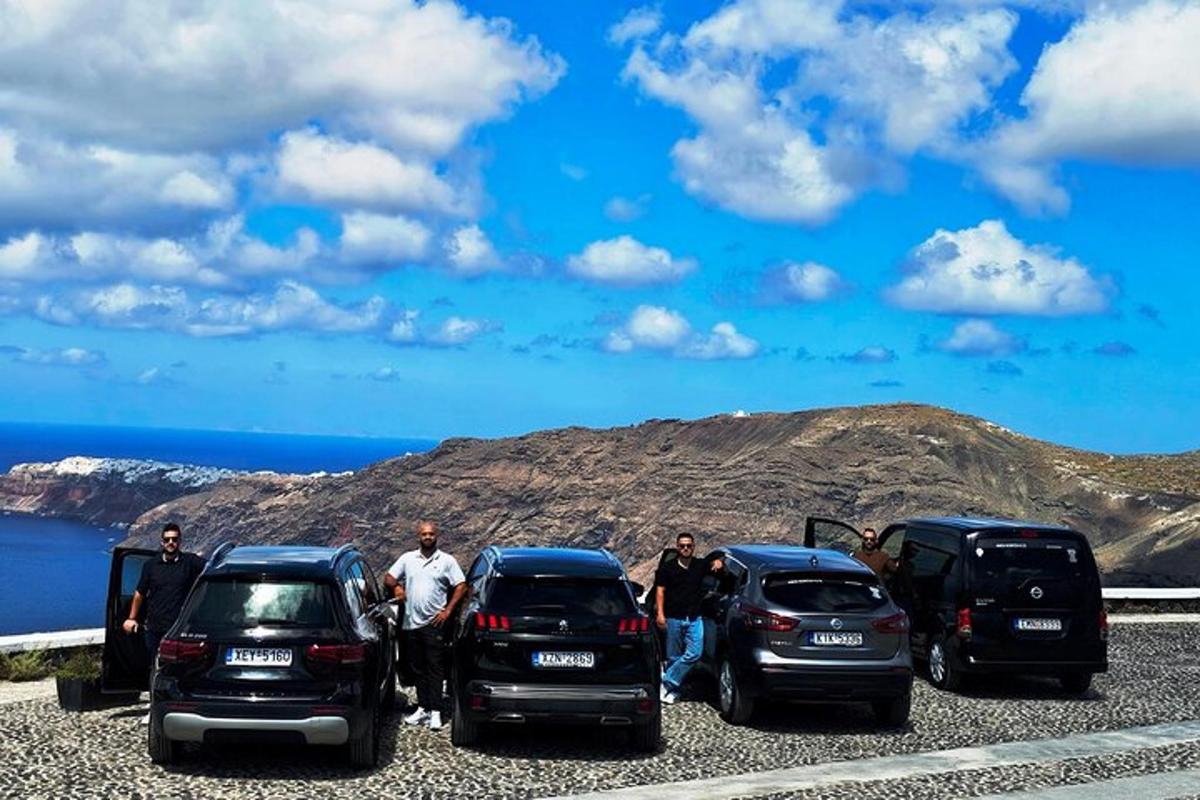 un gruppo di persone in piedi davanti a tre auto