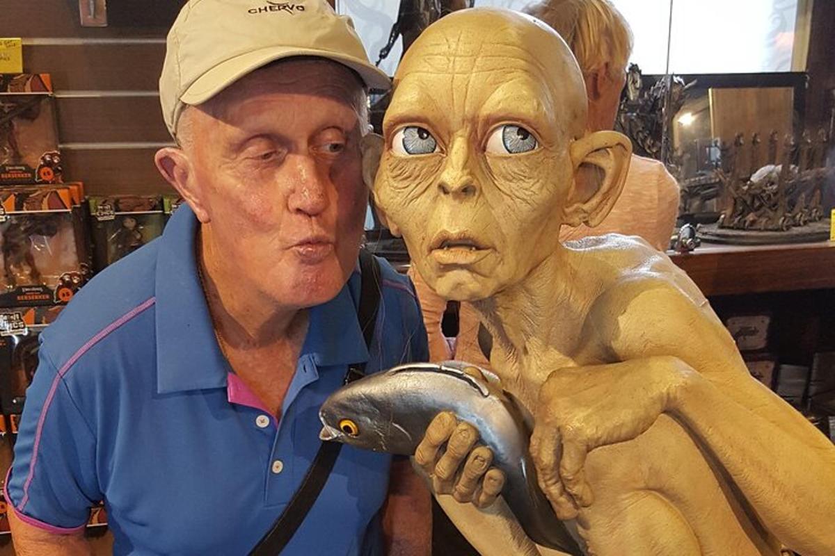 un uomo in piedi accanto a una statua di un uomo con una maschera