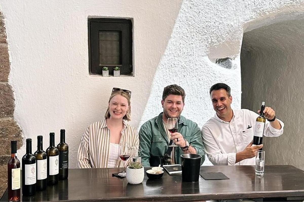 skupina lidí sedících u stolu s lahvemi vína