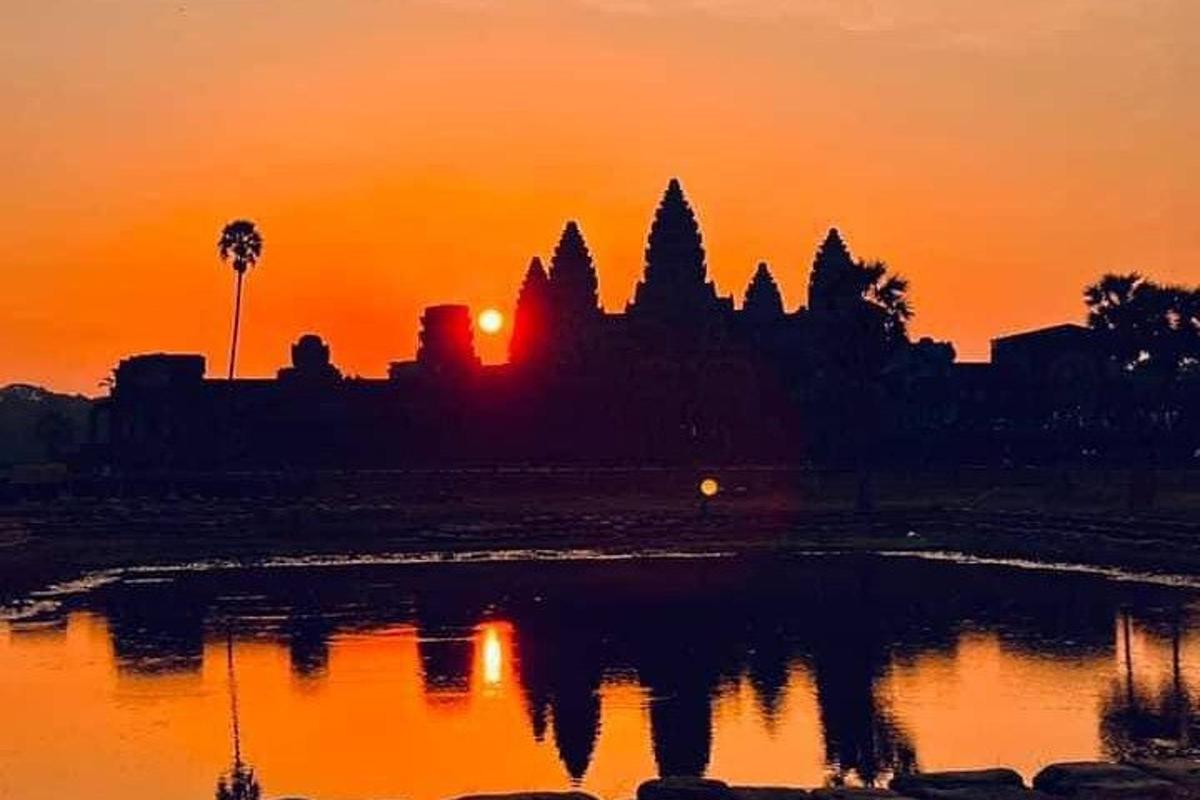 un tramonto con il riflesso di un tempio nell'acqua