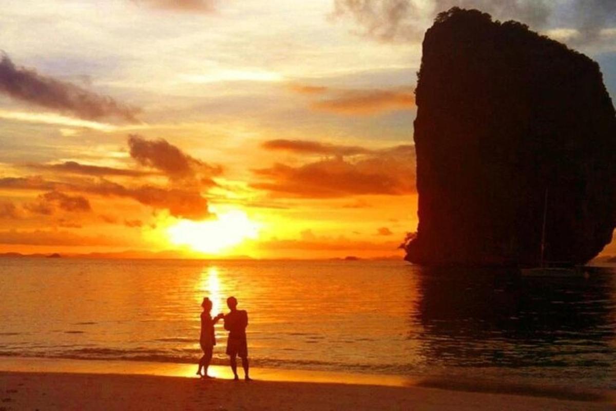 ビーチに立って夕日を眺めるカップル
