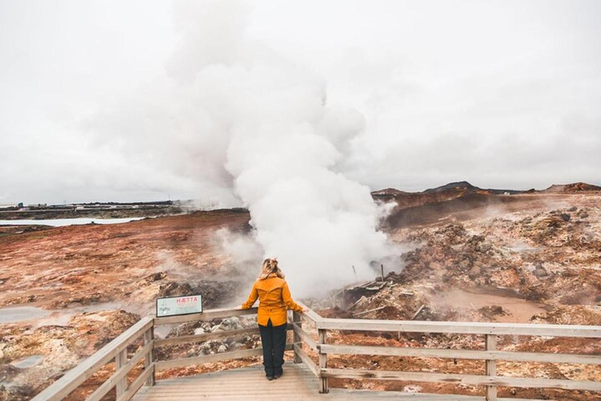 una donna in piedi su una passerella di fronte a un geyser
