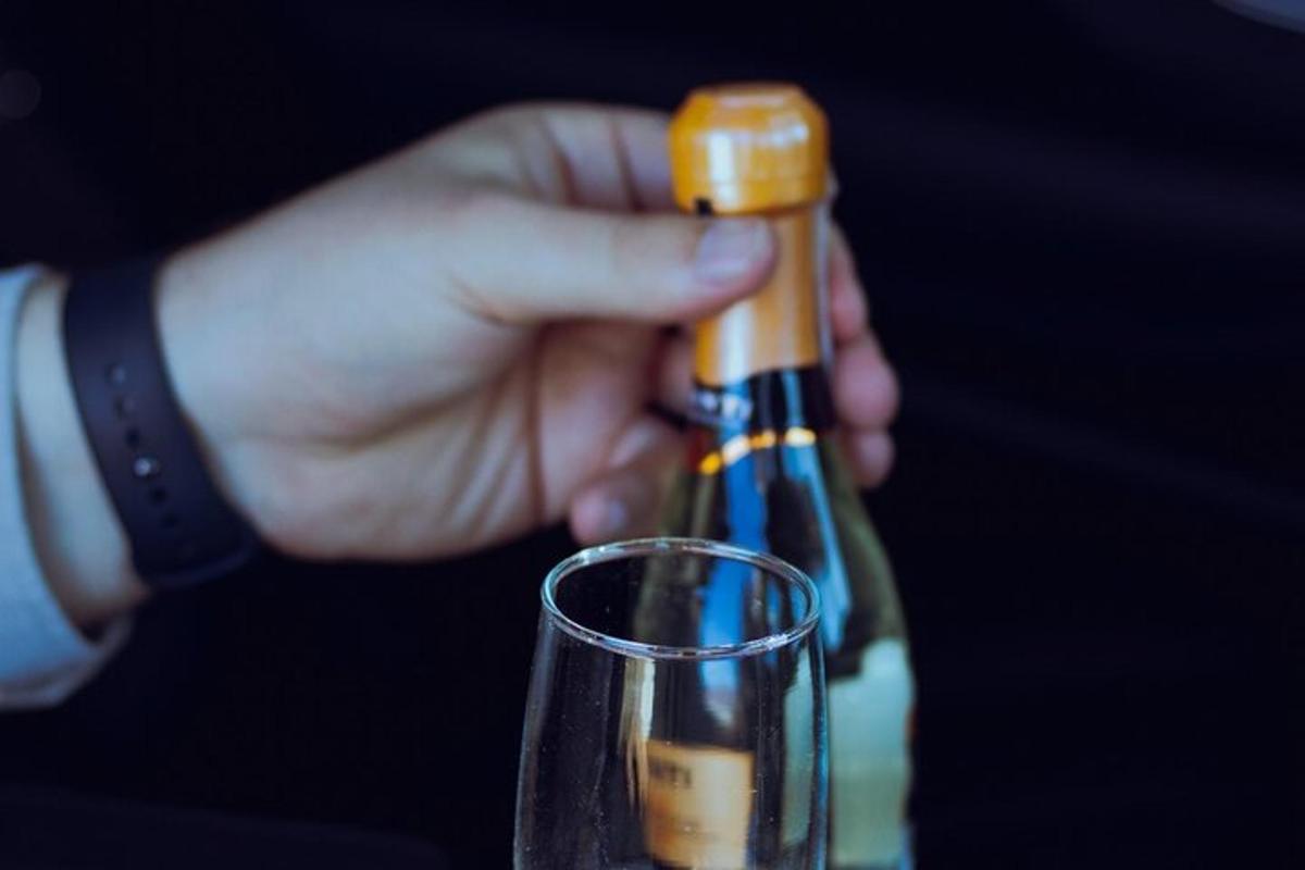 oseba, ki odpira steklenico vina poleg kozarca