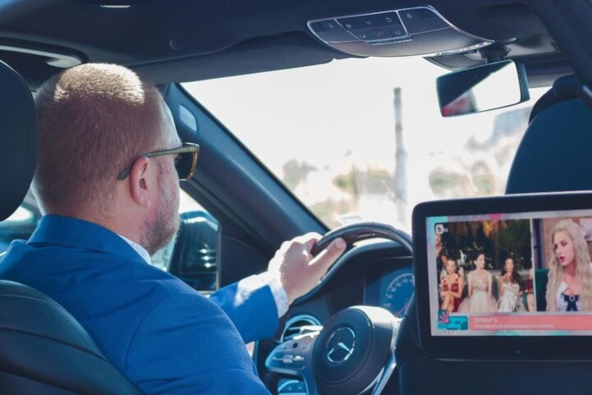 muž řídící auto s počítačem na volantu