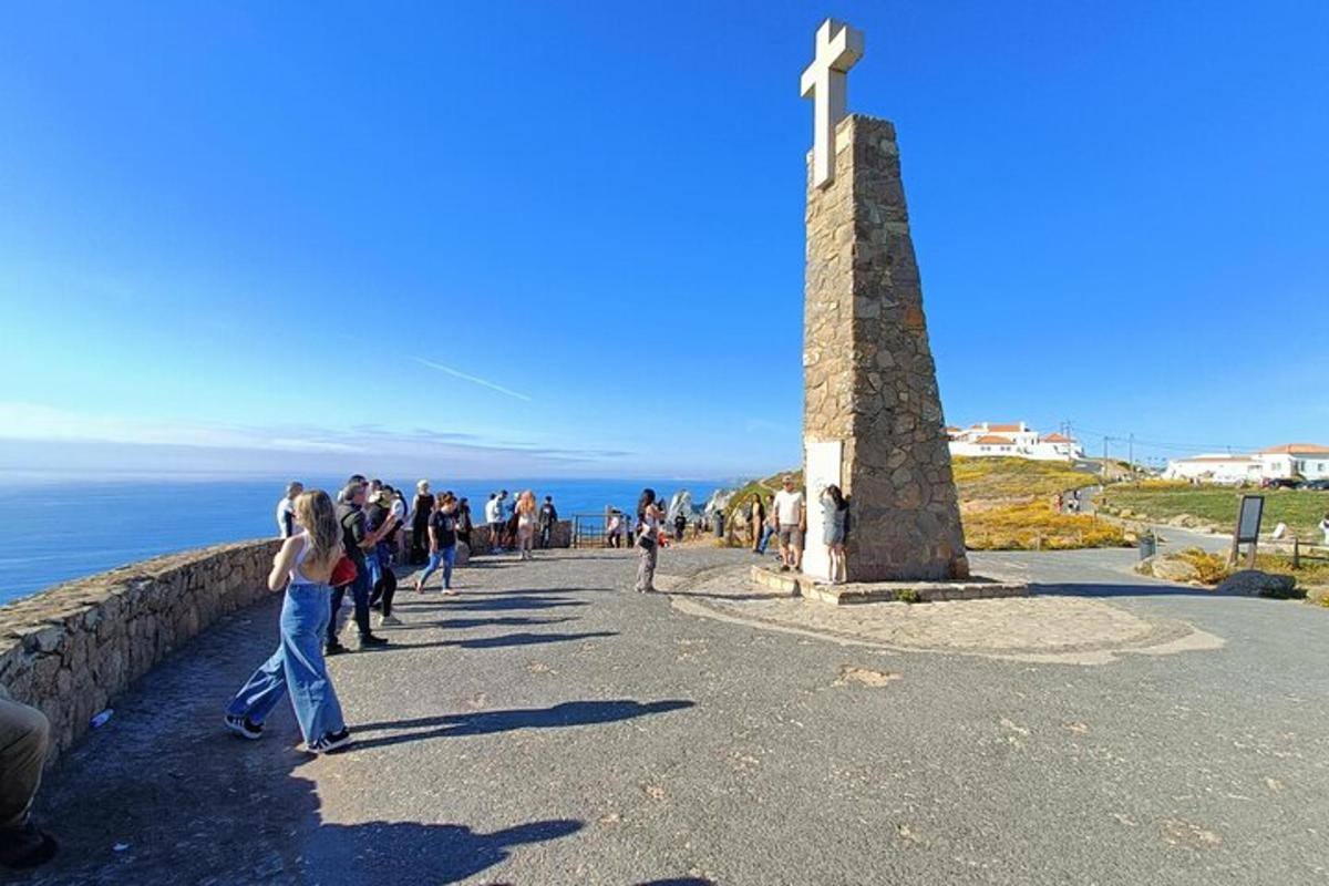 skupina ľudí kráčajúca okolo kríža na kopci