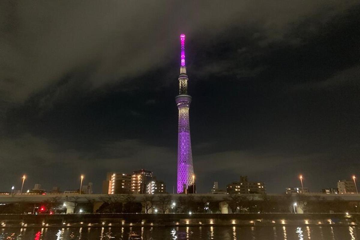 uma torre alta iluminada em roxo à noite