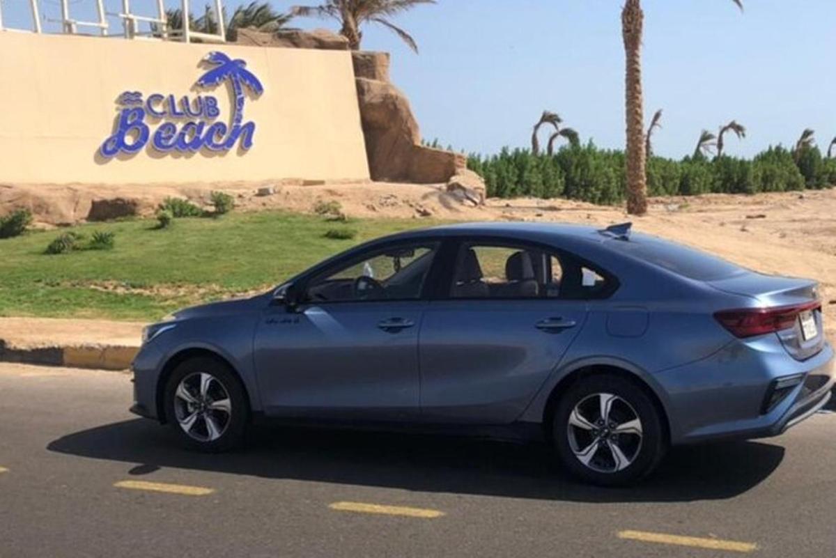 un cotxe blau aparcat davant d'una platja