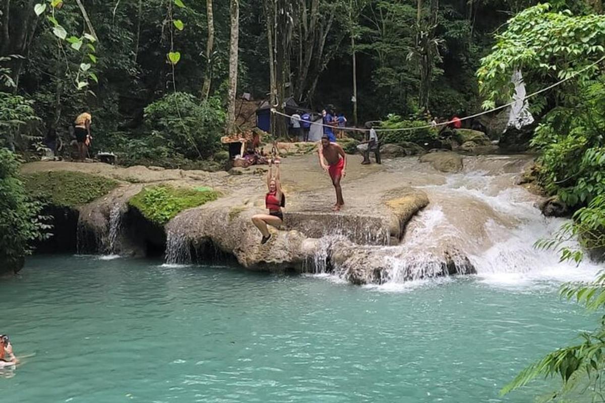 sekumpulan orang berdiri di dalam air terjun di sungai
