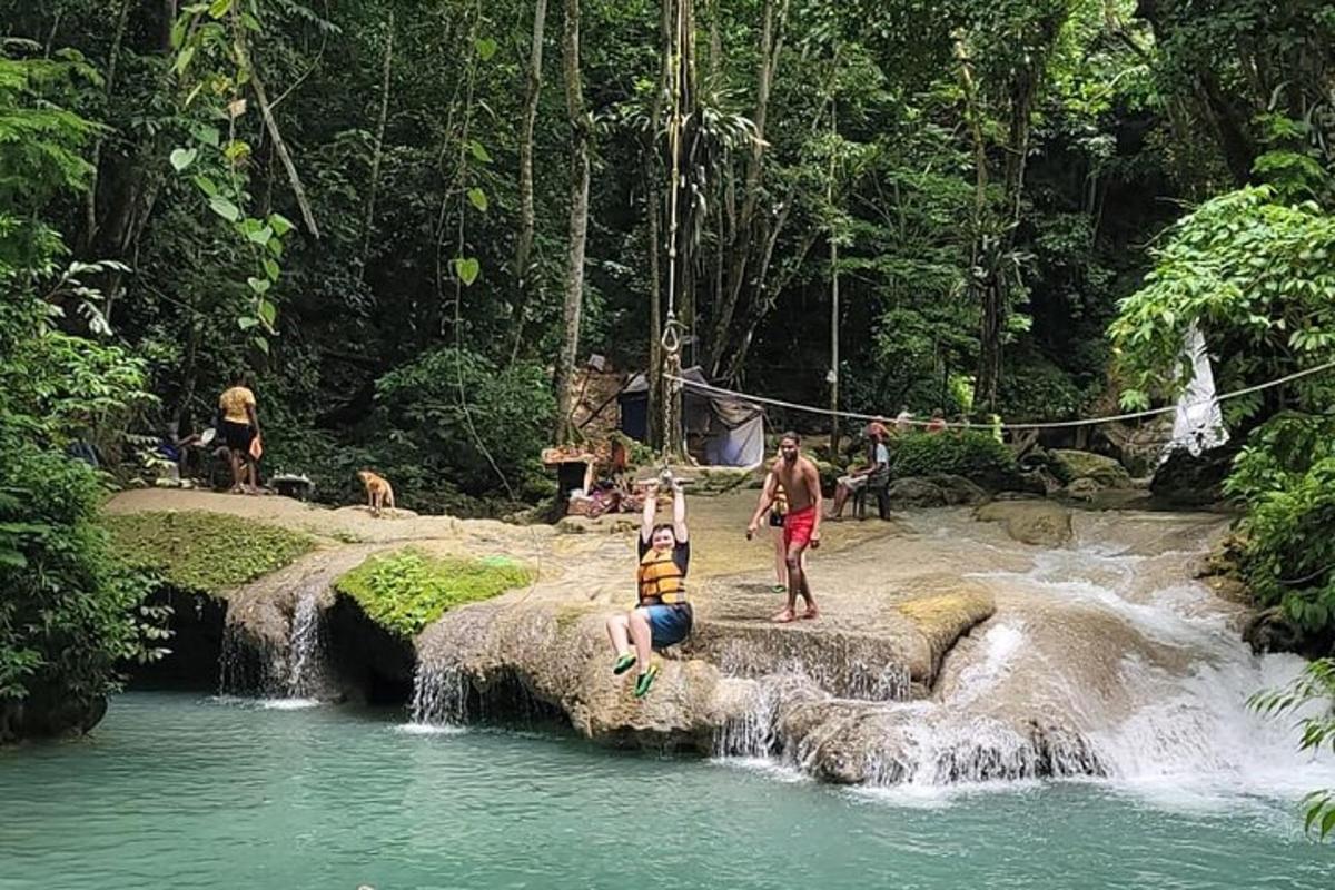 a group of people standing in the water near a waterfall