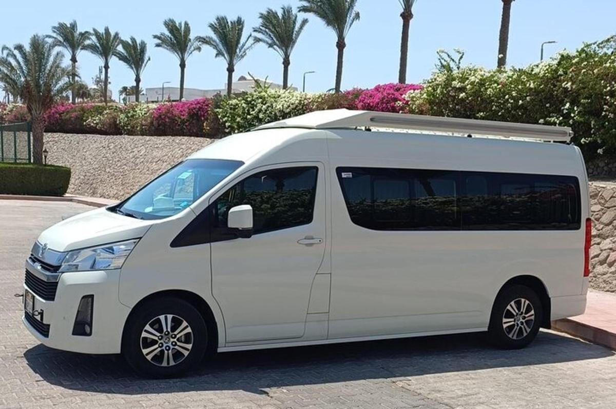bel kombi parkiran na parkirišču s palmami
