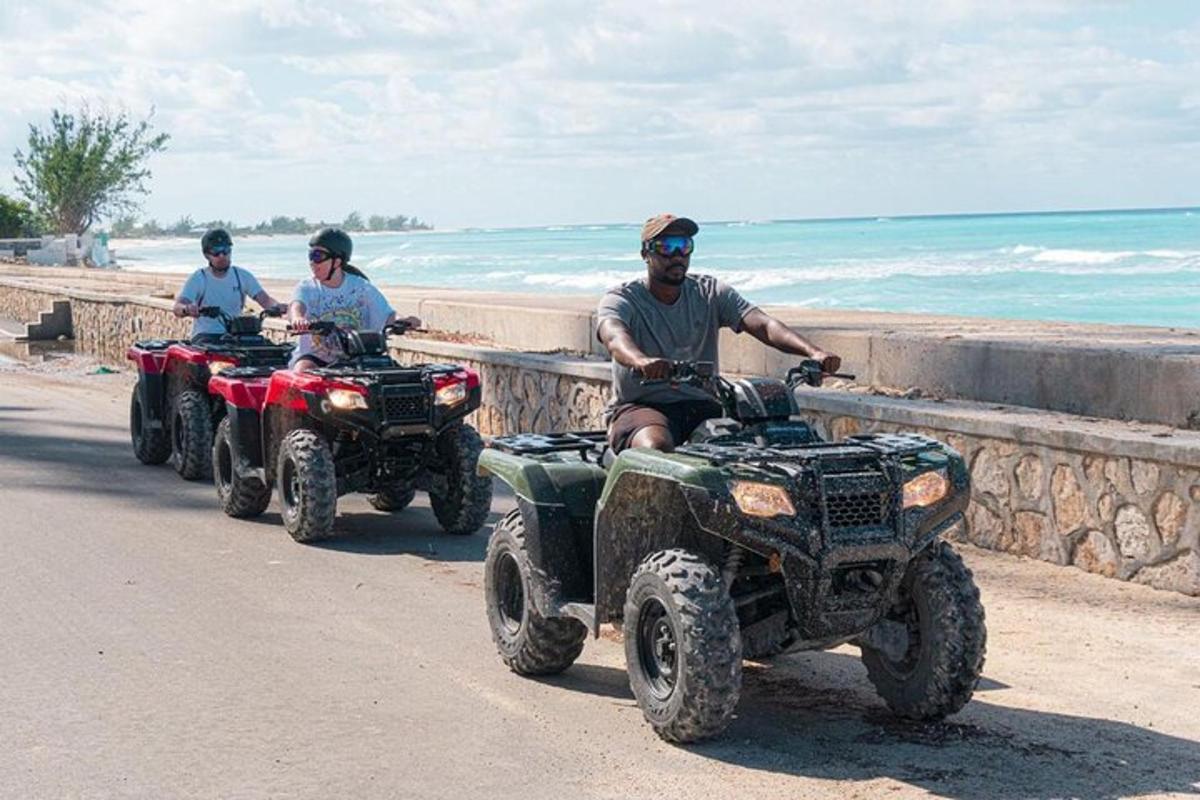 three people riding atvs on the beach with the ocean behind them