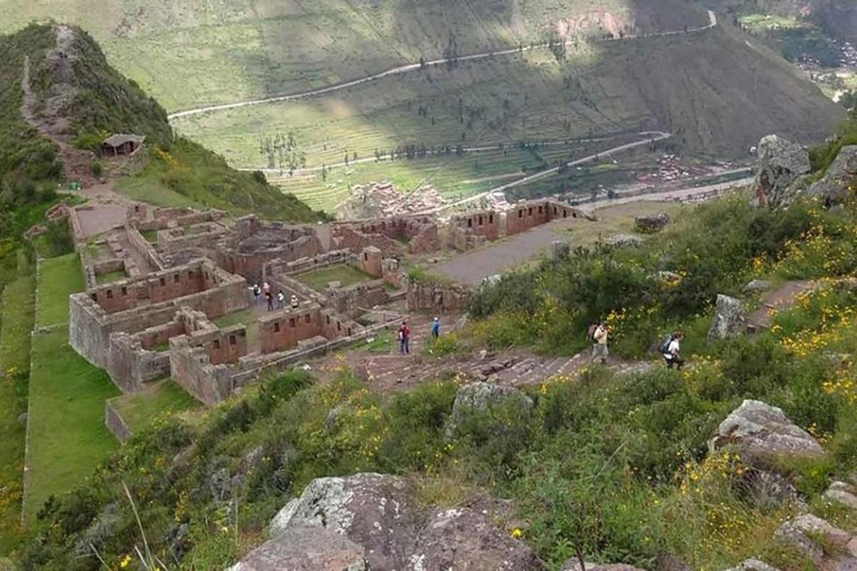 um grupo de pessoas caminhando ao redor de uma ruína em uma montanha