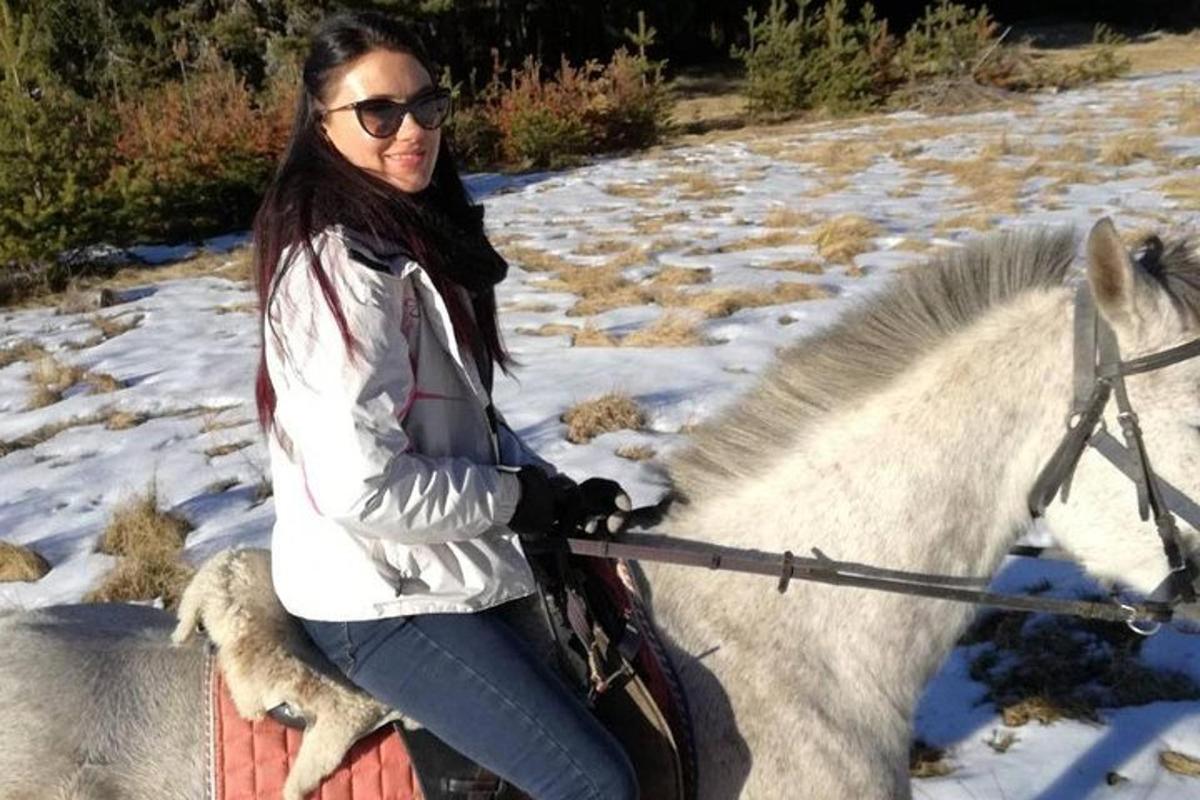 žena jedoucí na bílém koni ve sněhu