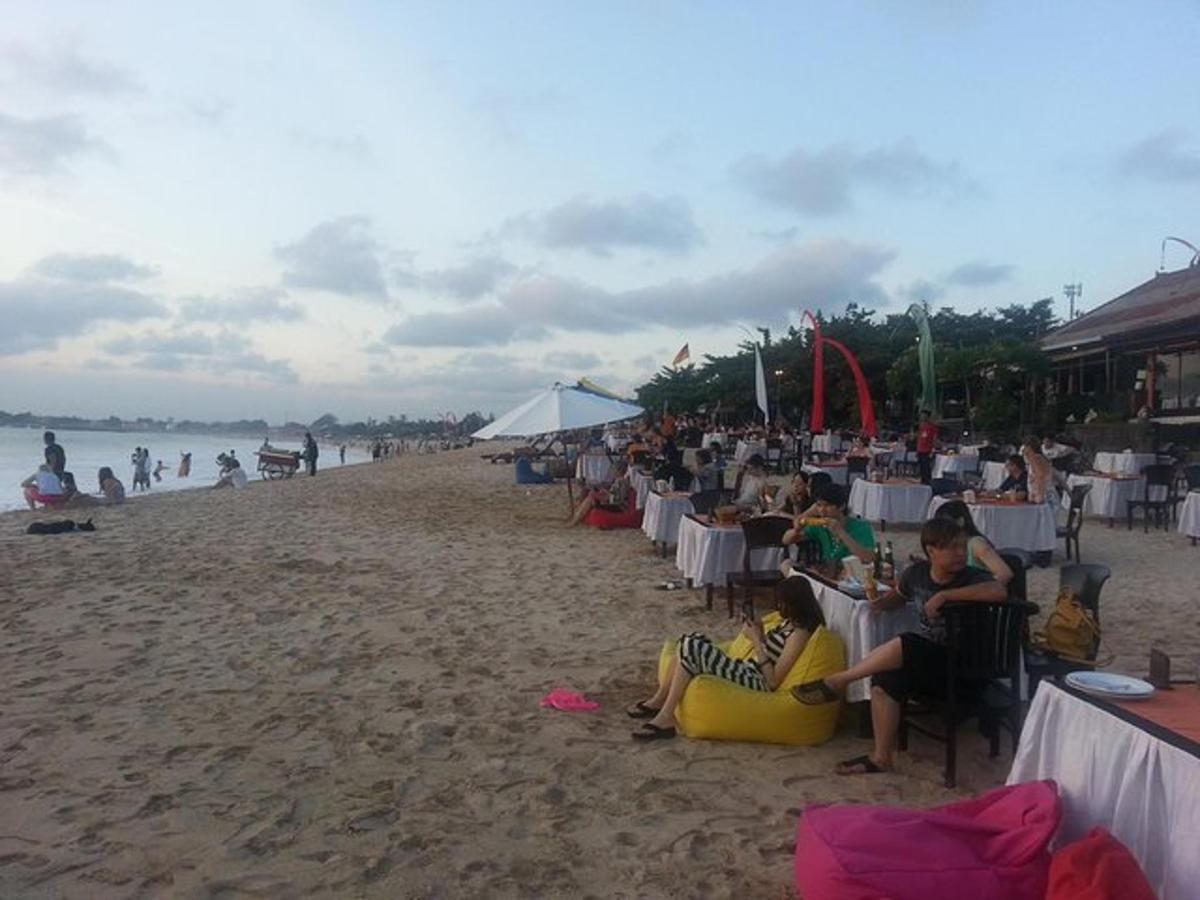 un gruppo di persone sedute ai tavoli su una spiaggia